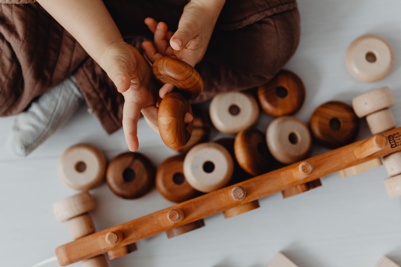Small hands holding smooth wooden rattles and rings
