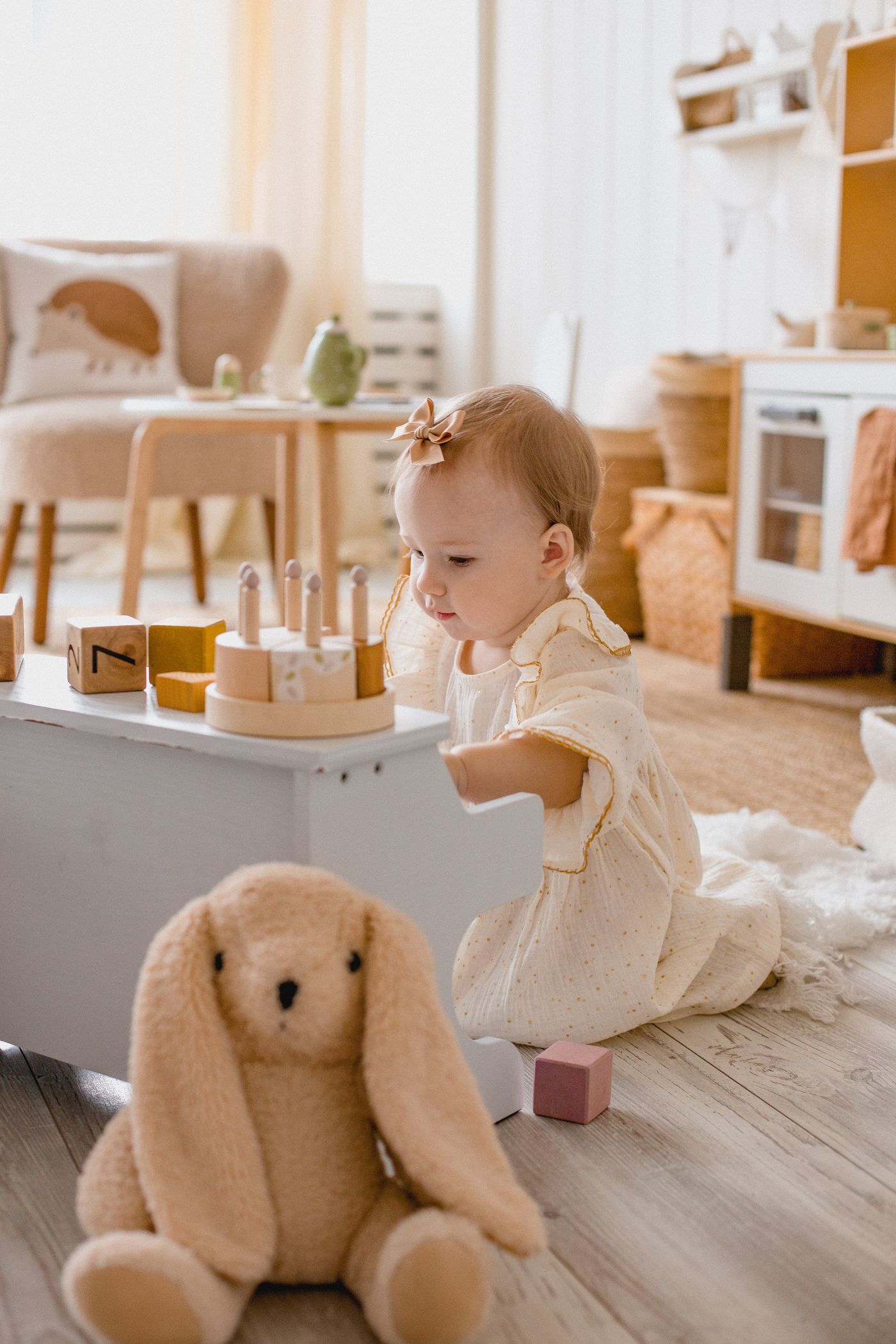 Toddler playing at a small wooden play kitchen in a sunlit room