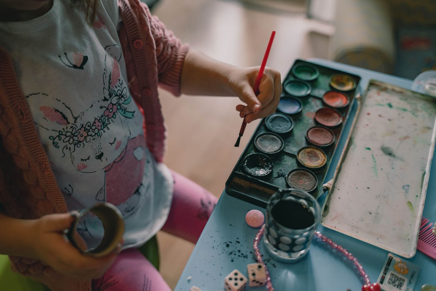 Young child painting with a brush at a craft table